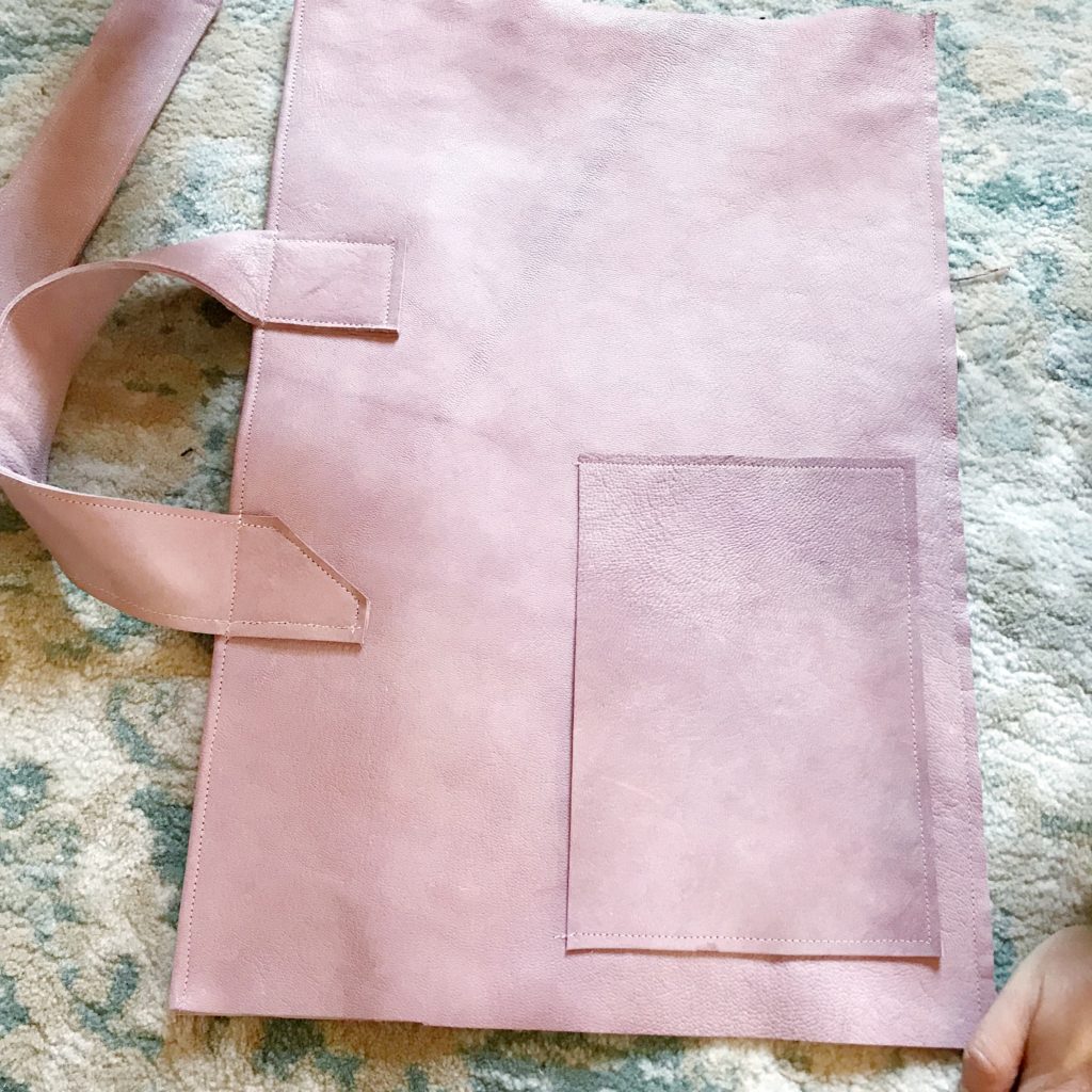 pink leather bag laid out on ground