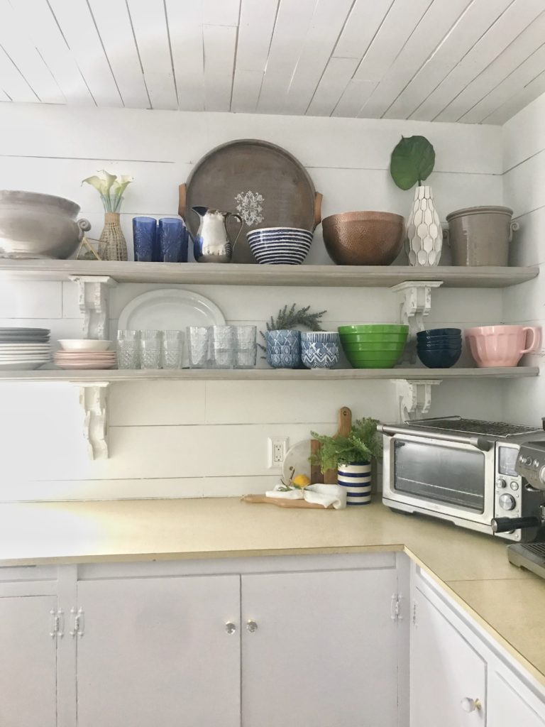 kitchen with 2 openshelves filled with bowlscups and plates