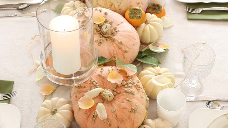 pumpkin on middle of table with glass candle holders and table set