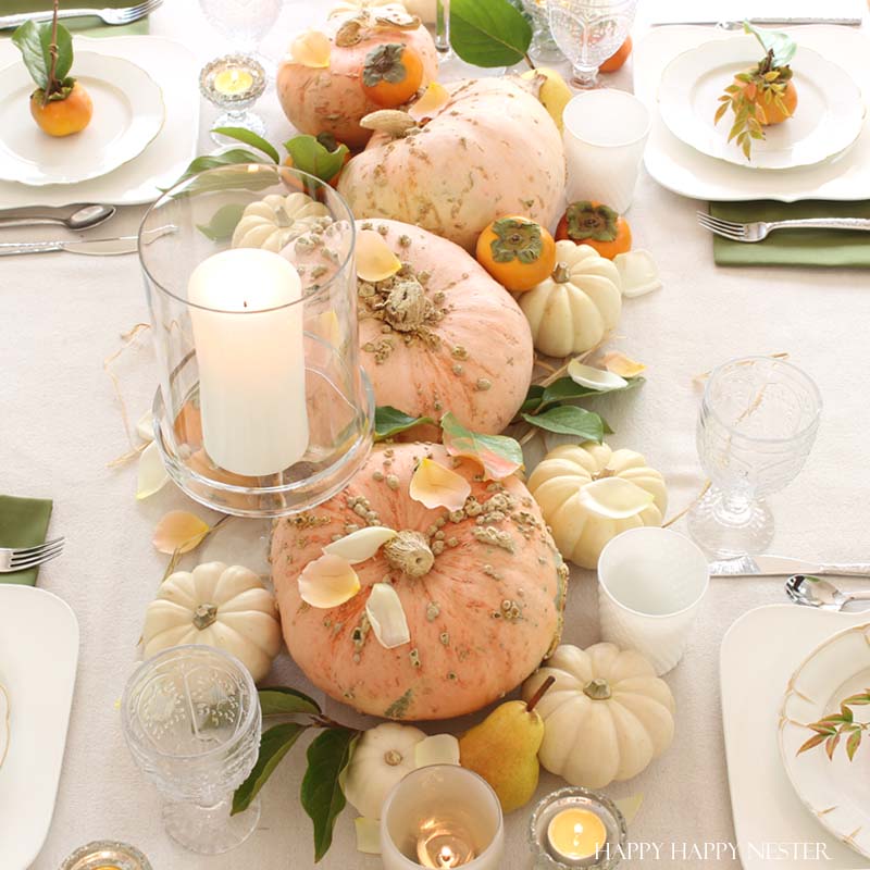 pumpkin on middle of table with glass candle holders and table set