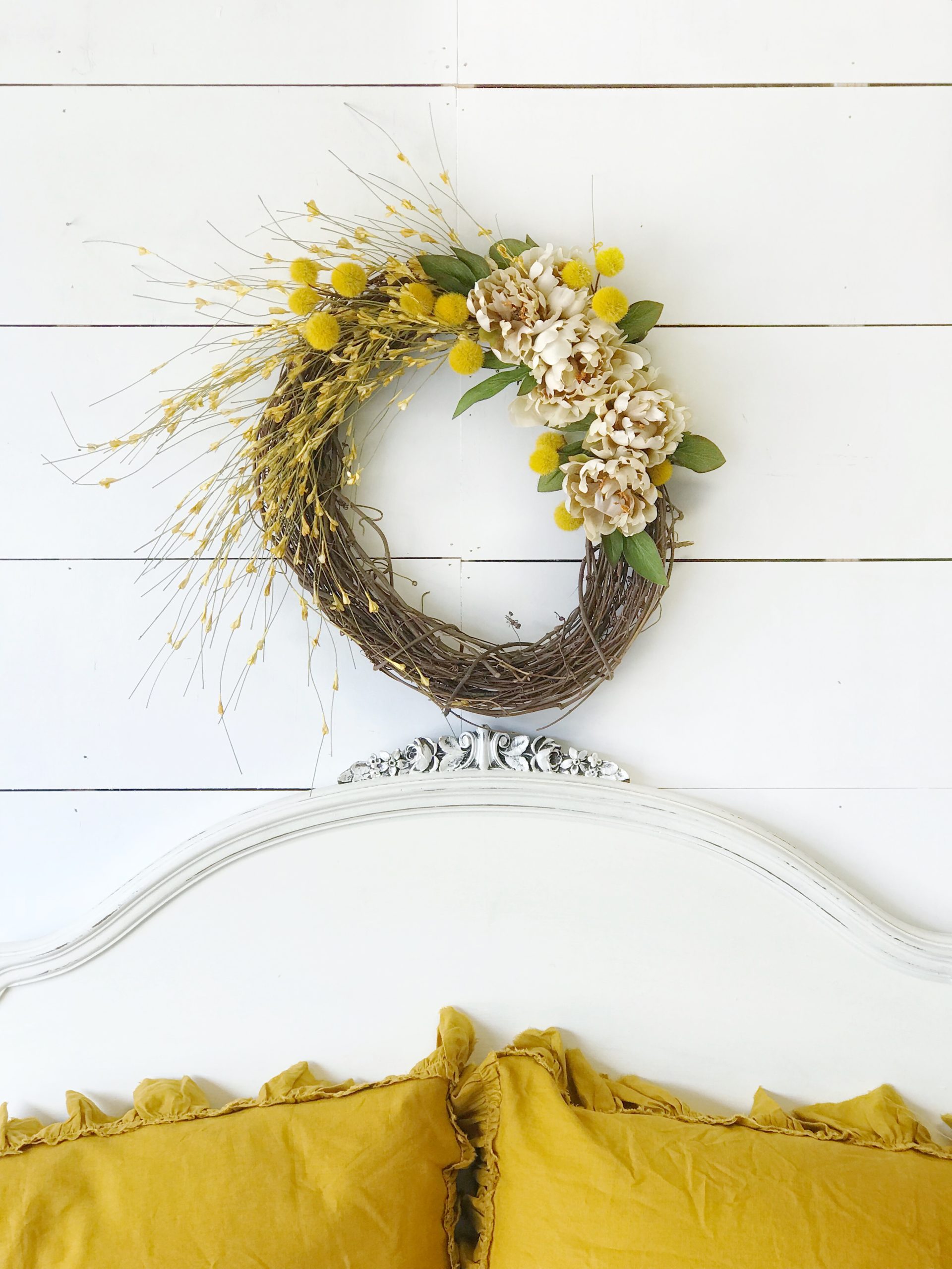 How to Make a Fall Wreath for Your Home wreath above white headboard and 2 yellow linen pillows