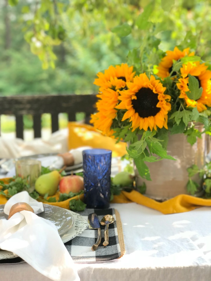 grey plate with gold silverware and bouquet of sunflowers