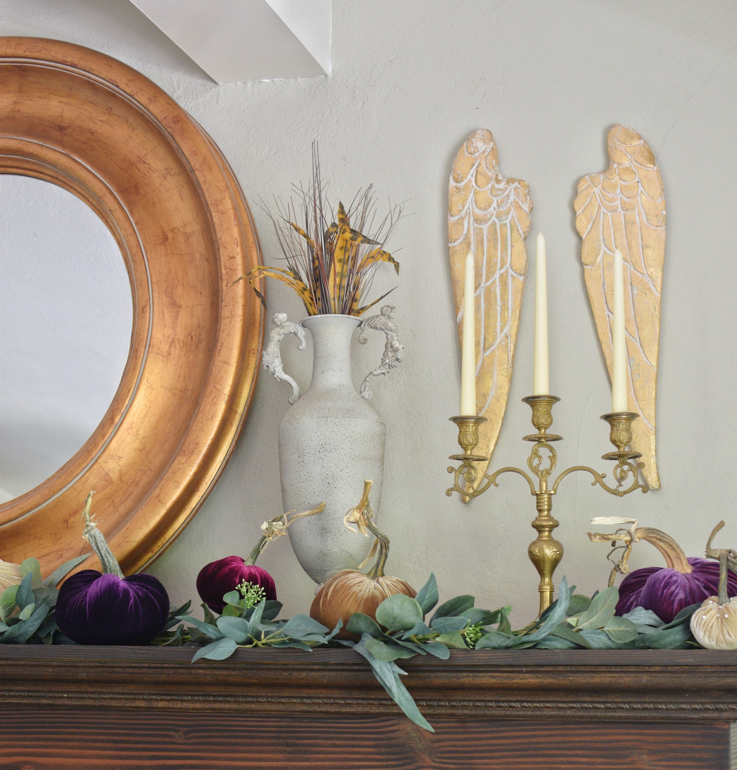 How to Style Beautiful Velvet Pumpkins on a Fall Farmhouse Mantel with 5 pumpkins and angel wings hanging with gold round mirror