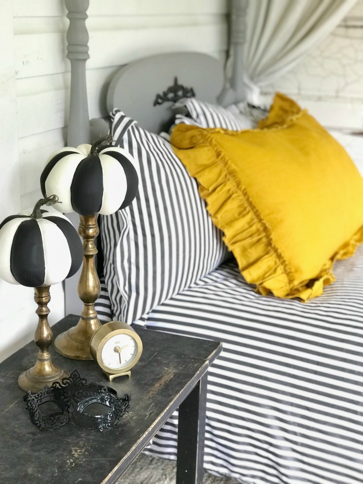 yellow and striped bedding with gold candle holdesr with striped pumpkins on top