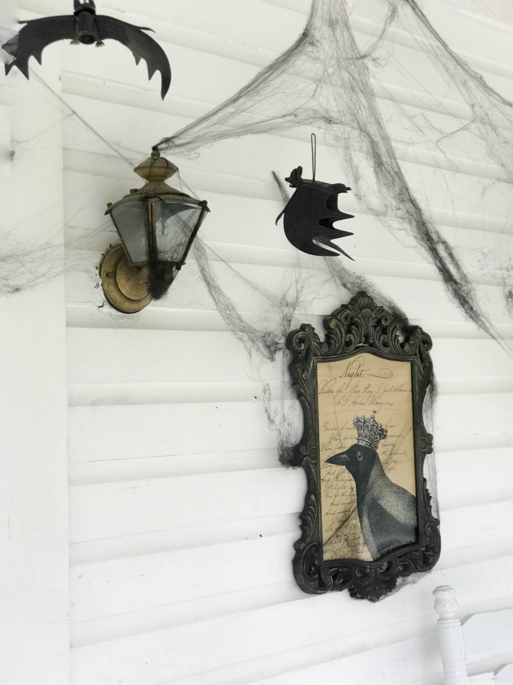 black frame with crow print and cobwebs with bats hanging