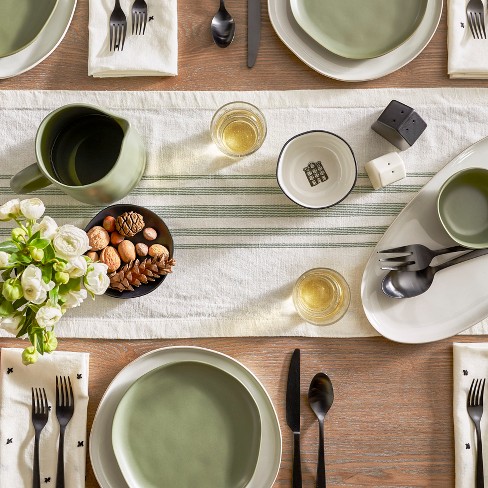 Magnolia Home with green and white table runner and green plates on top of white with black silverware