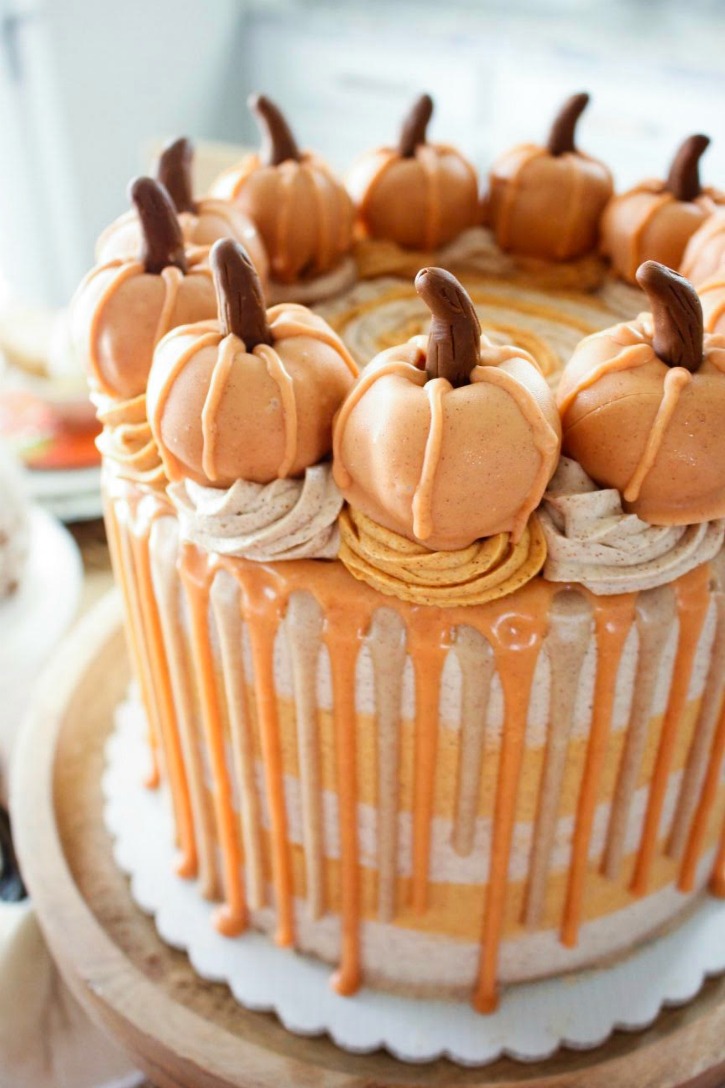 19 of the Best Pumpkin Fall Recipes with orange and white cake with dripped sides and cookie sandwiches on top with dollops of icing