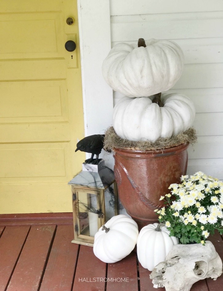 2 white pumpkins stacked with 3 on the ground and lantern with crow on it