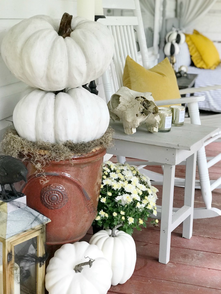 2 white pumpkins stacked with 3 on the ground and lantern with crow on it