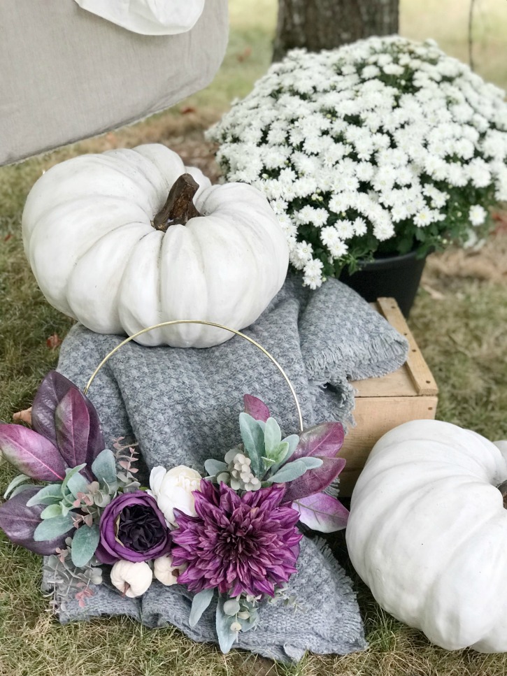 2 white pumpkins on crate with purple wreath and grey blanket with white mum